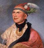 Oil on canvas of Joseph Brandt in colorful native American clothing and a head dress that includes a band and several green and white feathers. Small amounts of war paint adorn his cheeks.